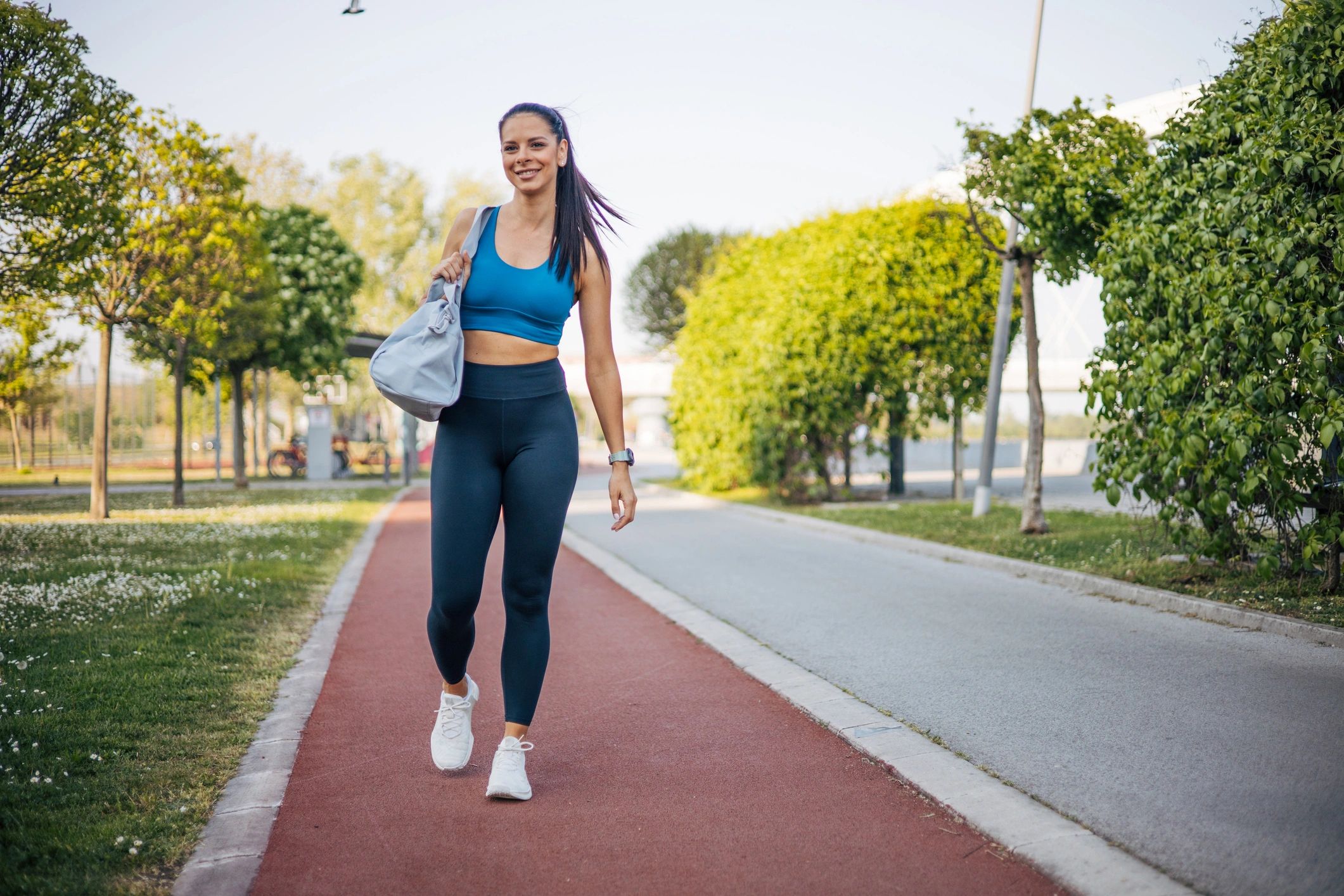 Sporty woman walking with a gym bag and exercise mat