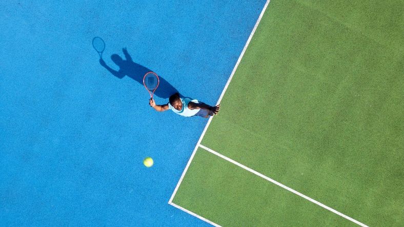 Tennis player preparing to serve on an outdoor court
